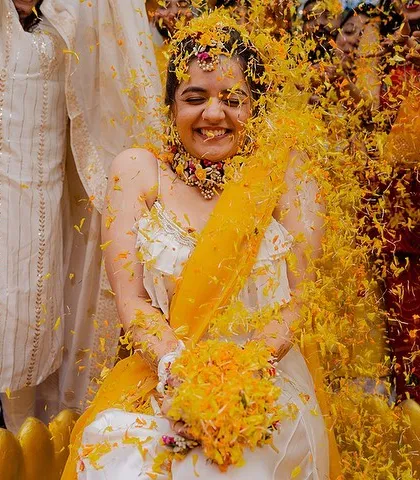A moment of pure joy as the bride is showered with flower petals during her Haldi ceremony. Her ecstatic smile says it all.