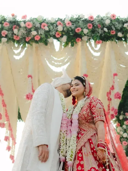 A sweet, stolen moment where the groom gives the bride a gentle kiss on the cheek after the Varmala.