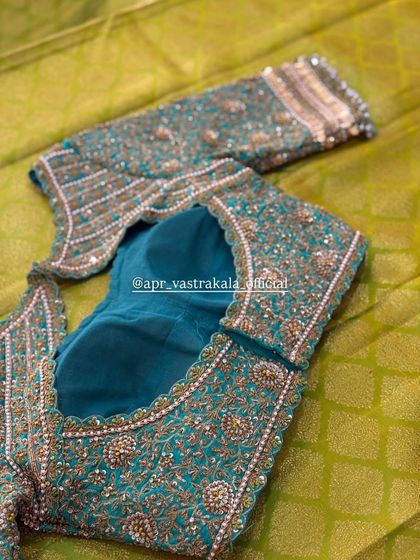 A teal blouse with heavy, intricate embroidery in shades of gold and silver.