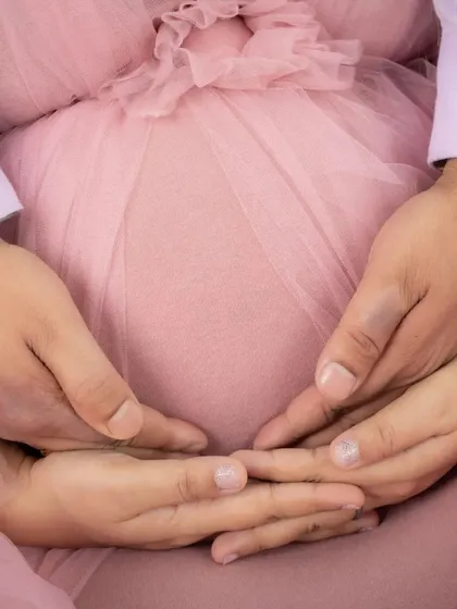 A close-up on the heart of the matter. This shot focuses on the hands of the parents-to-be cradling the baby bump, a simple and powerful symbol of their love and protection.