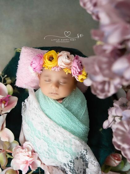 Wrapped in love and lace, this little one is surrounded by a frame of purple orchids. The framing of the shot draws all the attention to the baby's peaceful face.