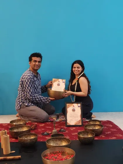 A student proudly holds her certificate after completing the sound healing program, ready to apply her new skills.