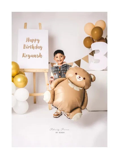 This three-year-old is having fun with a giant teddy bear balloon during his birthday photoshoot.