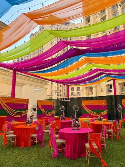 The full view of the outdoor Mehendi, with multiple seating areas and food stalls, all under the colorful canopy.