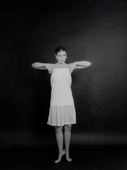 A black and white studio shot for Tululs against a dark background. The pose is inspired by dance, creating a sense of movement and grace within a minimalist setting.