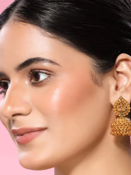 A detailed close-up of a model wearing traditional temple jhumkas. This shot is perfect for highlighting specific items within a larger collection, focusing on the intricate design and craftsmanship.