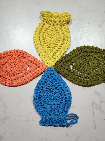 A flat lay of four pineapple pouches, showing their unique shape and lacy texture. The pattern is simple and works up very quickly.