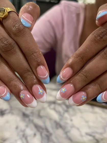 A sweet and fresh design combining a classic French manicure with baby blue tips and hand-painted daisies. A perfect look for spring.