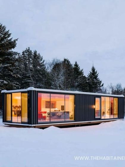 A modern container home with large glass windows, set in a snowy landscape to demonstrate its all-weather durability.