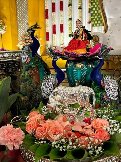 A centerpiece for a puberty ceremony featuring a doll surrounded by four peacock figures.