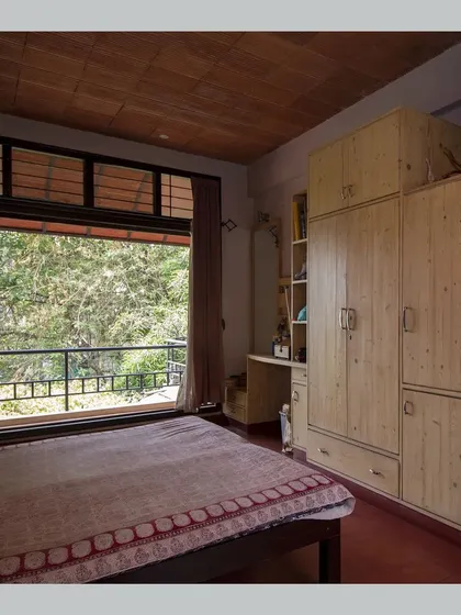 A bedroom that opens onto a balcony, offering beautiful views of the surrounding trees and greenery.