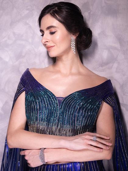 A poised and elegant shot, highlighting the structure of the couture gown and the sleek, polished hair and makeup.