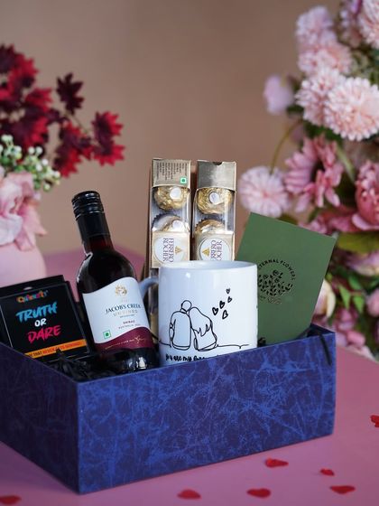 The 'A Toast to Love' hamper presented in a stylish blue box against a romantic floral background.