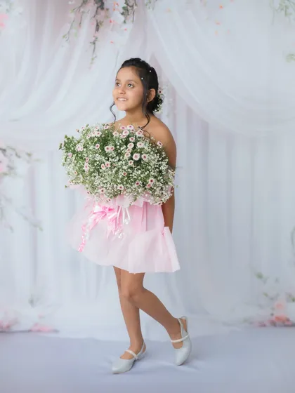 A full-length portrait showing off her pretty pink dress and the elegant, draped backdrop.