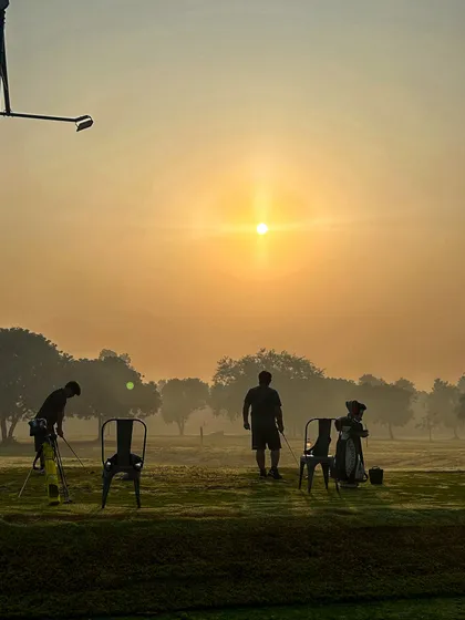 Silhouettes of golfers against the hazy sunrise, a peaceful and inspiring start to the day.