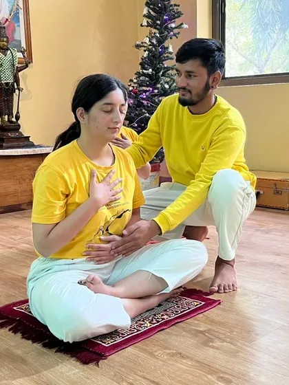 An instructor guides a student in proper yogic breathing, a fundamental part of our beginner course that helps calm the mind.
