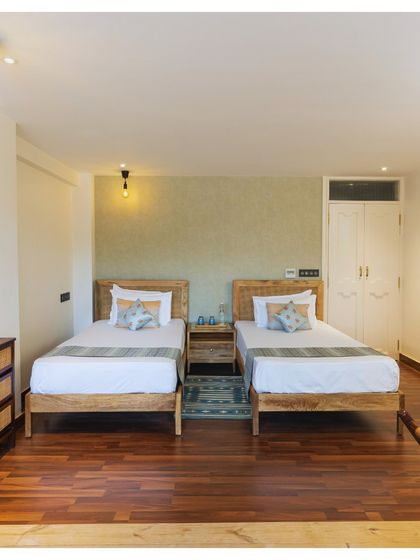 Another example of Somya's design, a serene twin bedroom with a focus on natural wood, rattan details, and a calm color palette.