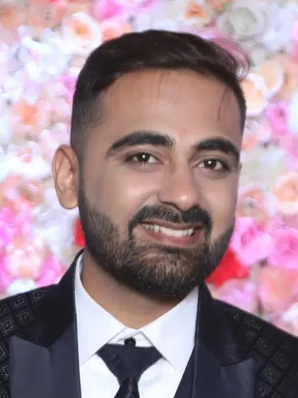 A close-up of the groom against a flower wall. The makeup enhances his skin tone and gives him a radiant look for his reception.