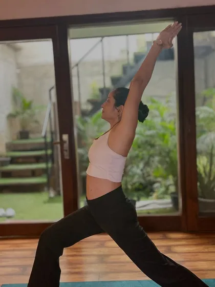 Warrior I pose, shown here, is excellent for building strength in the legs and core, helping to tone the midsection.
