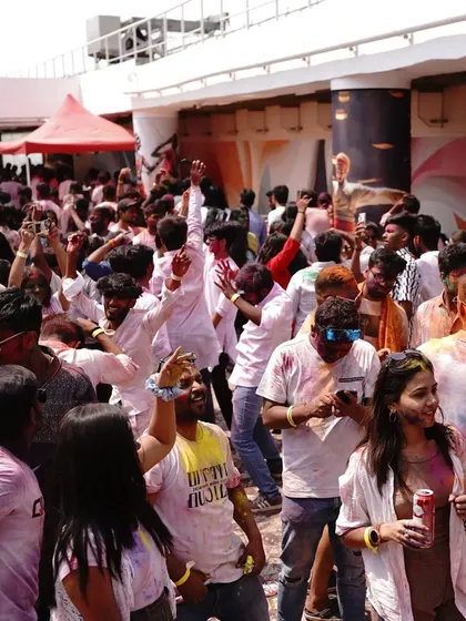 The dance floor is a sea of color and movement. This is the beautiful chaos of a Holi party.