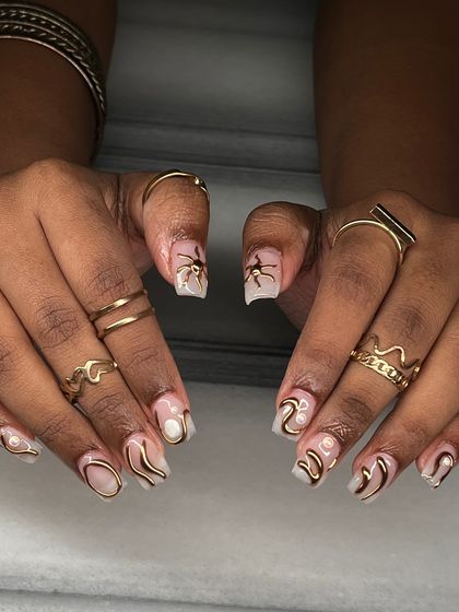 Abstract art for your nails. This set features free-flowing, raised gold chrome lines over a milky white base, accented with tiny pearls for a modern and artistic design.