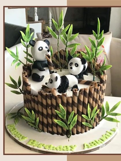 An adorable panda-themed cake with fondant pandas playing amongst chocolate wafer stick bamboo.