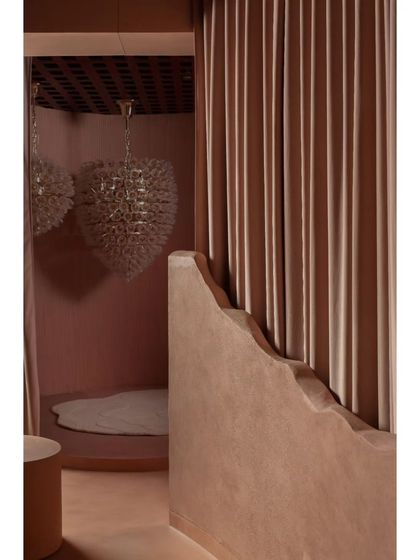 A glimpse into one of the curated alcoves, where a stunning crystal chandelier is reflected in a mirror. The scalloped edge of the wall adds a soft, handcrafted detail to the design.