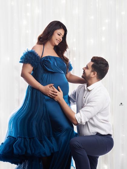 A romantic pose with the dad-to-be kneeling to be close to the baby bump. The client's beautiful blue gown and the soft lighting create a tender and loving atmosphere.