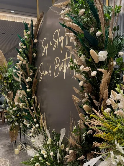 "Sip n Slay" was the theme for this birthday. We created a lush, earthy backdrop using pampas grass, dried palms, and white florals, which perfectly framed the custom signage.