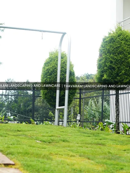 A slightly different angle of the swing set and lawn, showing the stone path and the property's boundary fence.