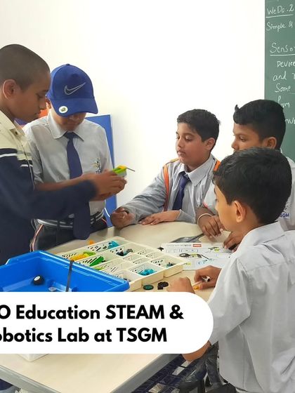 A team of boys at TSGM collaborates around a table, working on a LEGO project. Our instructor has written key concepts like 'Sensor' on the board to guide the lesson.