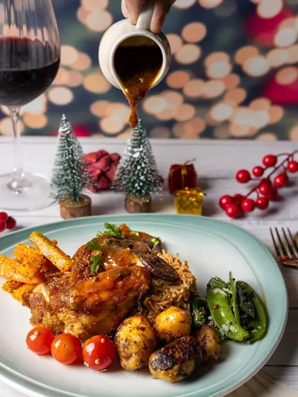 A festive Christmas dinner scene complete with a glass of red wine and holiday decorations in the background.