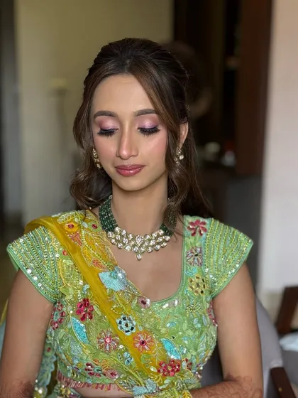 This Haldi look features a half-up style with a twisted detail and soft waves, adorned with a small hair accessory.