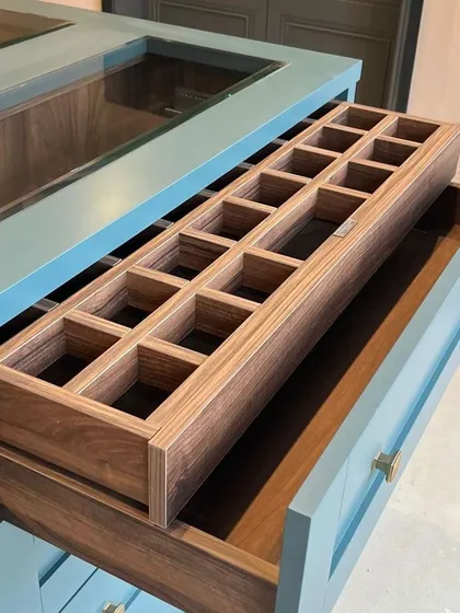 A close-up of the custom organizer tray inside our wardrobe island. Crafted from wood, these compartments are perfect for keeping watches, cufflinks, and jewelry neatly arranged.