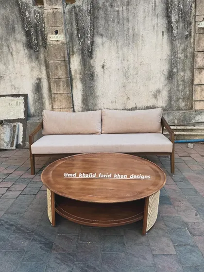 Front view of the neutral-toned sofa and round teak coffee table.
