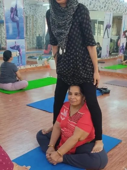In our inclusive classes, students often help each other. Here, one participant assists another in opening her hips in Butterfly Pose, demonstrating the community spirit of our studio.