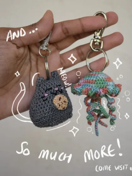 A showcase of two different keychain styles: a sleepy cat with a cookie and a colorful jellyfish. This shows the variety of amigurumi charms I create in my shop.