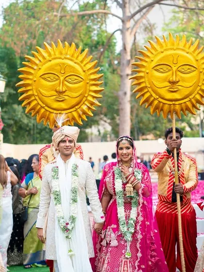 The happy couple walks together, surrounded by dancers and attendants holding golden sun props. This kind of coordinated, themed procession ensures your entry as a couple is a shared, joyous experience.
