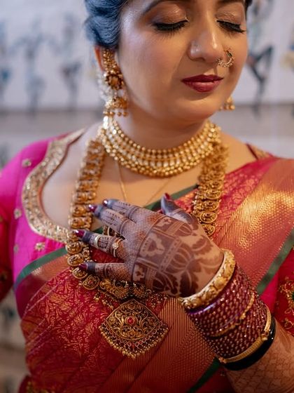 A serene portrait of the bride in her pink saree, her hand gently resting on her chest, showcasing the beautiful henna stain.