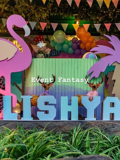 A close-up of the custom "LISHYAN" name display in pastel blue, set against a backdrop of lush greenery and party decorations.