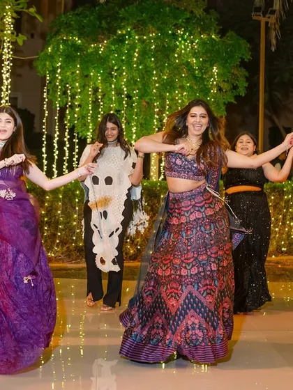 A group of friends dancing together under a canopy of fairy lights.