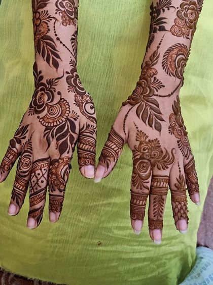 A beautiful floral design with delicate vines connecting the patterns. The fingers have detailed work that complements the main design on the hands and wrists.