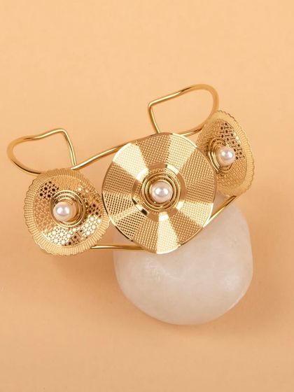 The gold floral cuff bracelet styled on a white stone for a natural, earthy feel.