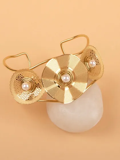 The gold floral cuff bracelet styled on a white stone for a natural, earthy feel.