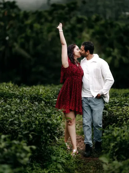 A playful and romantic kiss shared by a couple in a tea plantation, their joy evident in this candid pre-wedding photo.