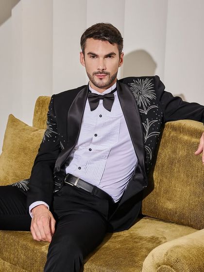 Relaxed yet refined, this image shows the embroidered black tuxedo in a comfortable setting. The bespoke tailoring ensures it looks just as good sitting down as it does standing up.