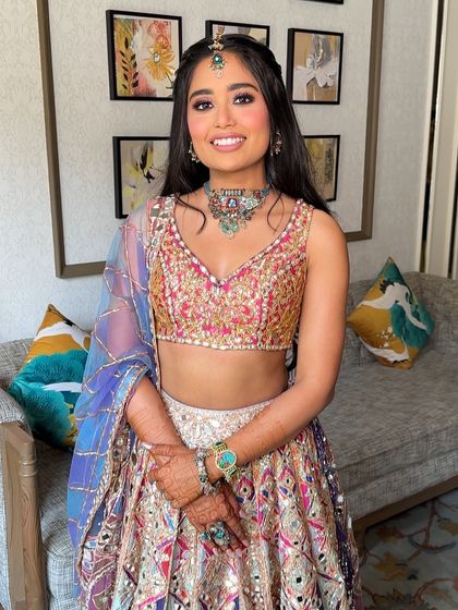 The bride looking joyful and radiant, her playful hairstyle perfect for a daytime Mehendi party at a destination wedding.