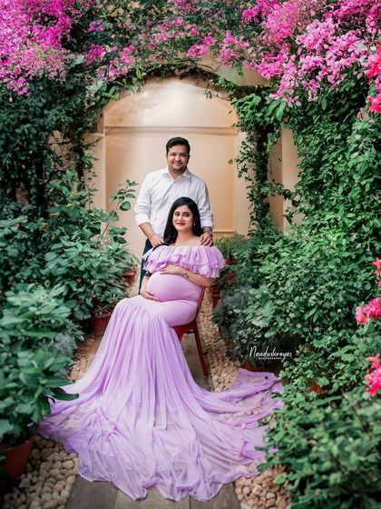 A beautiful portrait of the couple seated amidst a garden of flowers. The way the lavender gown drapes on the ground makes this a truly stunning maternity photo.