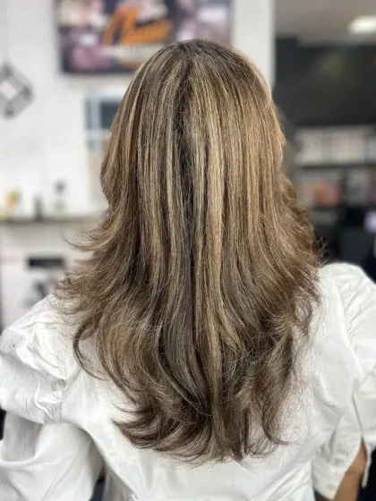 A multi-layered haircut with highlights, creating incredible texture and dimension. This is a great example of a modern feather cut.