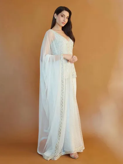 Nora Fatehi looks ethereal in this white peplum and sharara set by Ritika Mirchandani. This is a great example of fusion wear, blending traditional embroidery with a modern silhouette for a chic, celebratory look.